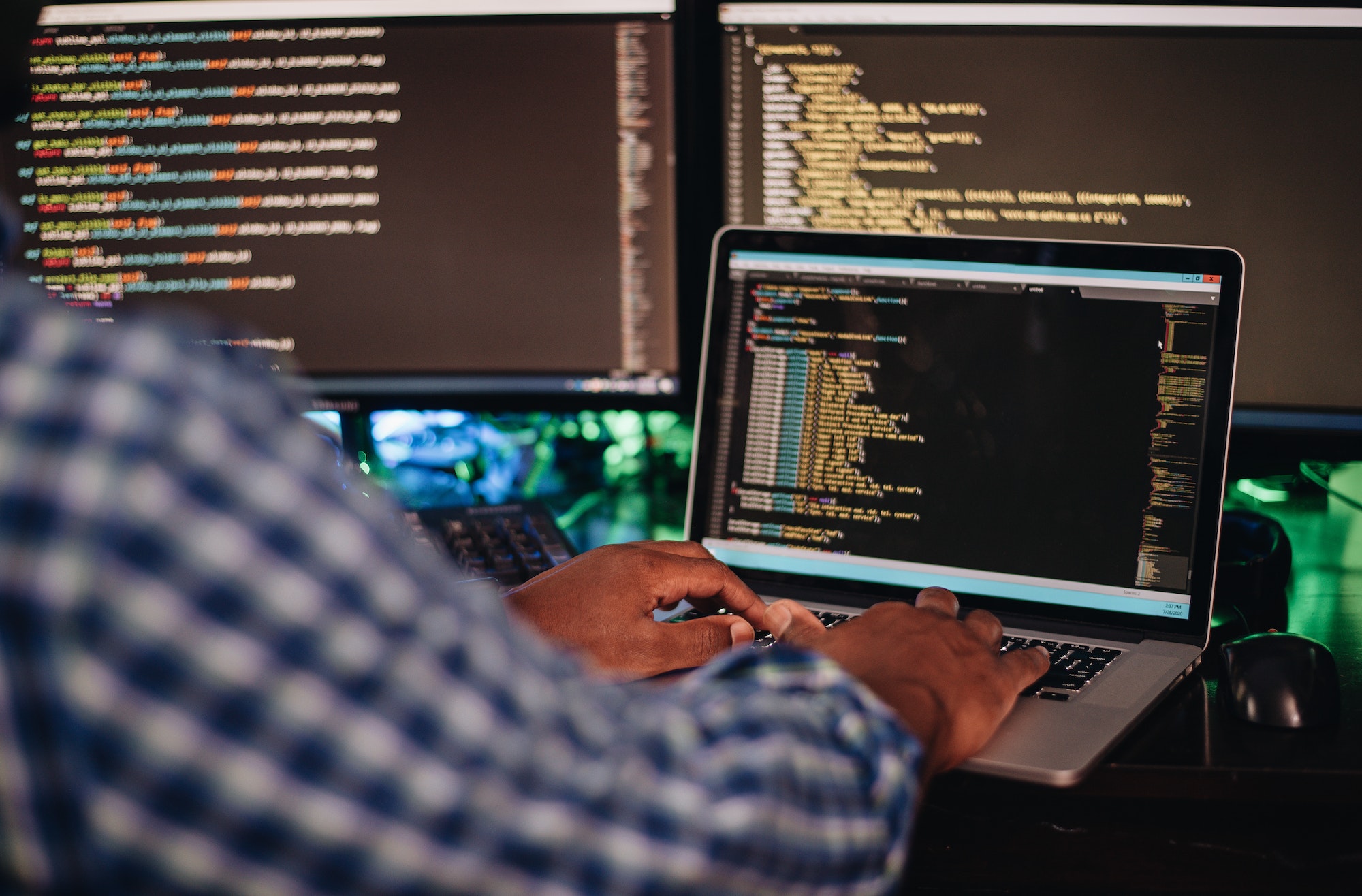 African American man sitting at a computer developing software through coding